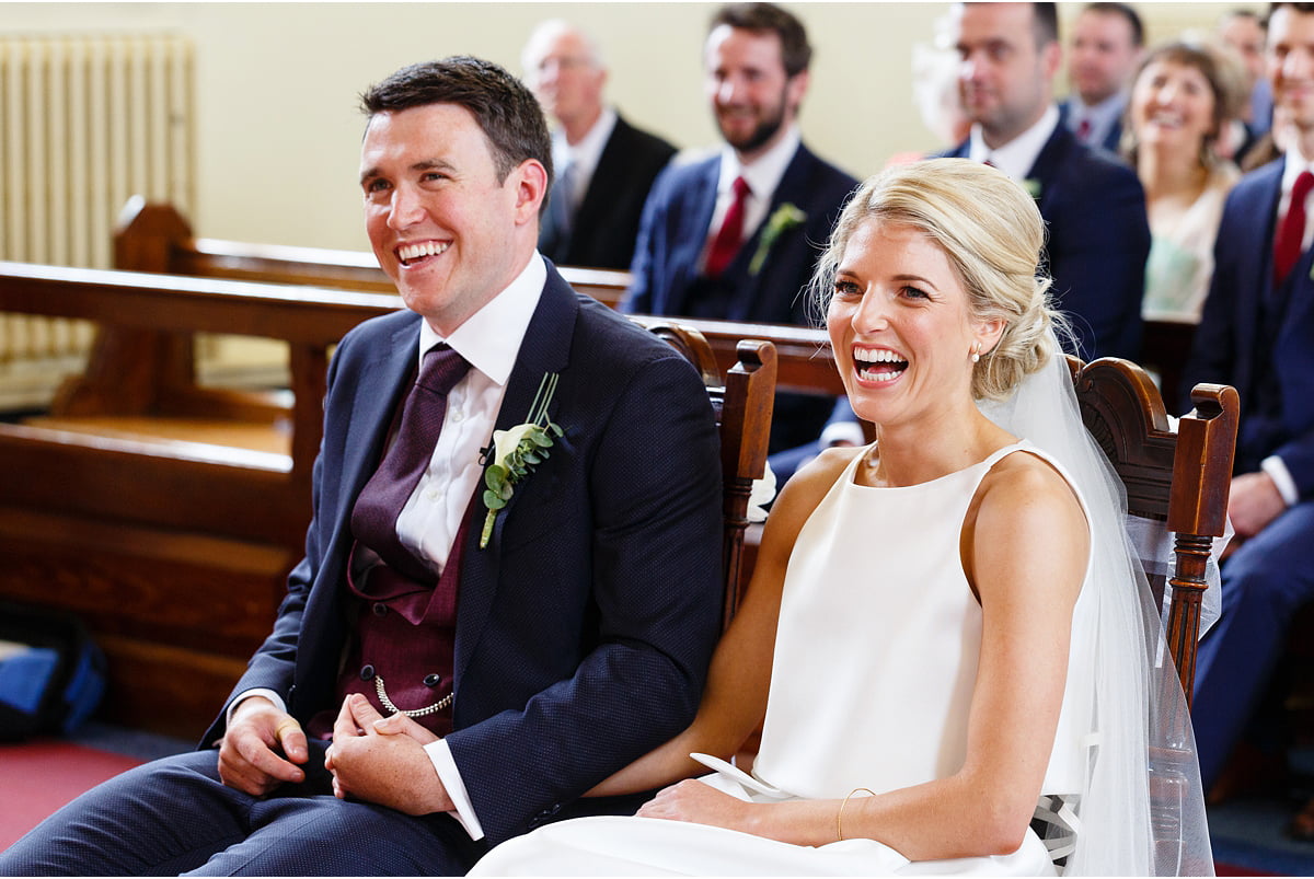 bride and groom laughing at something priest just said