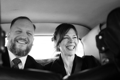 bride and groom beeming in the back of their wedding car