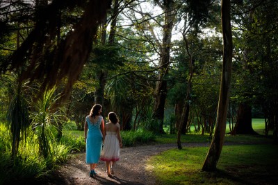 Brides walk through the beautiful light between the trees at Dromquinna Manor
