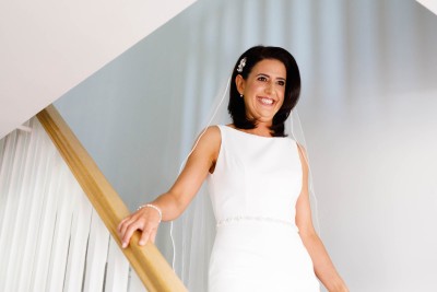 beaming bride comes down the stairs before her wedding in Fota