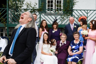 Man laughing heartily while formal family photographs are being taken