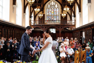 bride hides her face from wedding guests as they stand to cheer. A very special wedding in the Aula Maxima in UCC