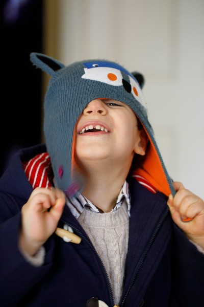 small boy pulls on his wooly hat