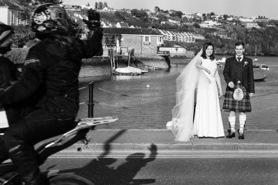 people on a motor bike wave as they pass a bride ad groom at this Kinsale Wedding