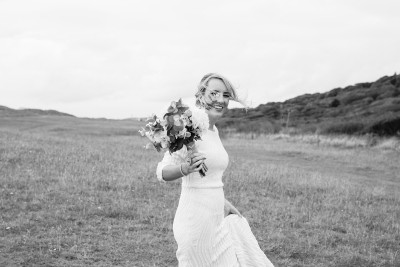 Brides hair blows in the wind as she crosses the sand dunnes in Kerry