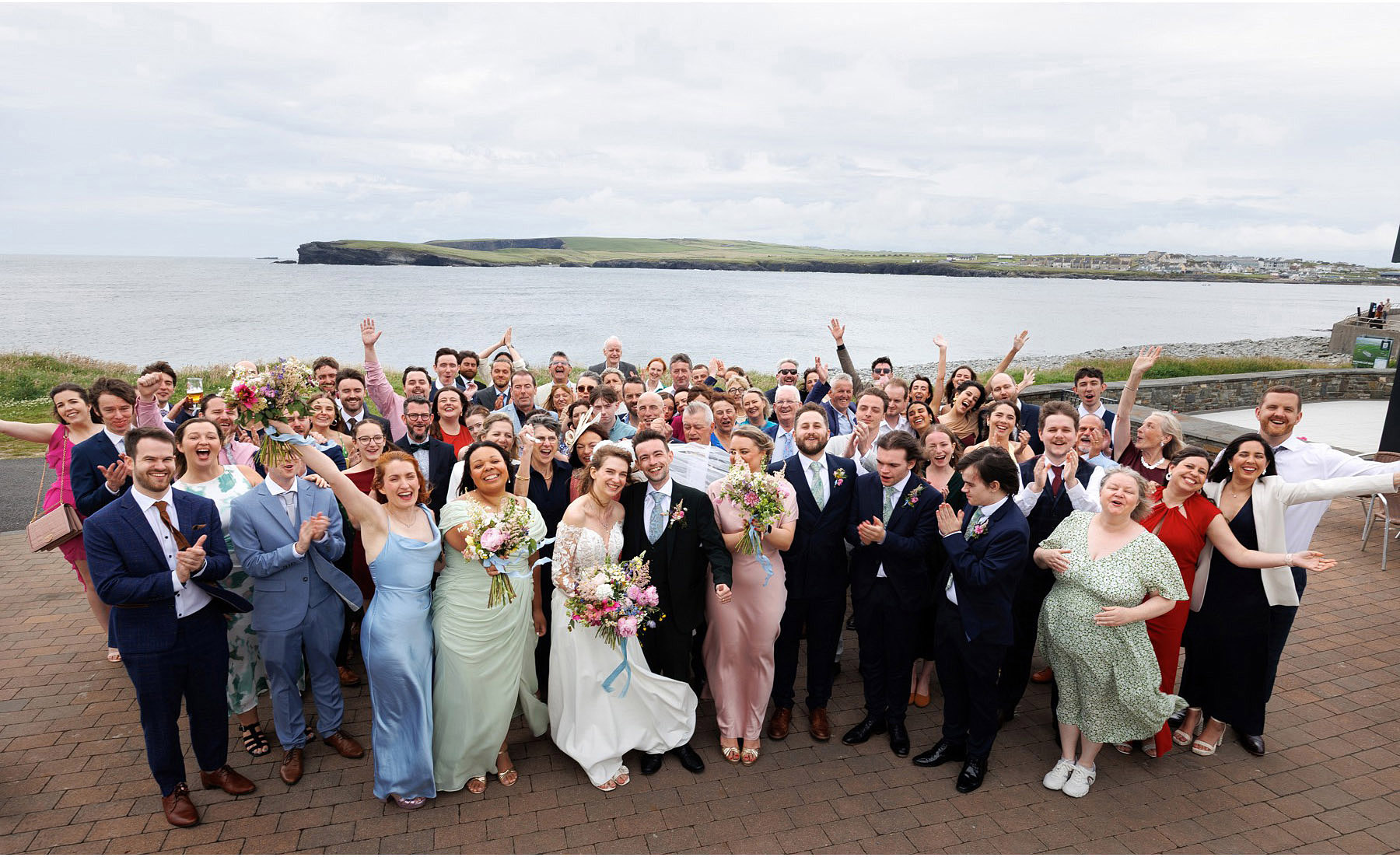 big wedding group outside diamond rocks with kilkee view behind
